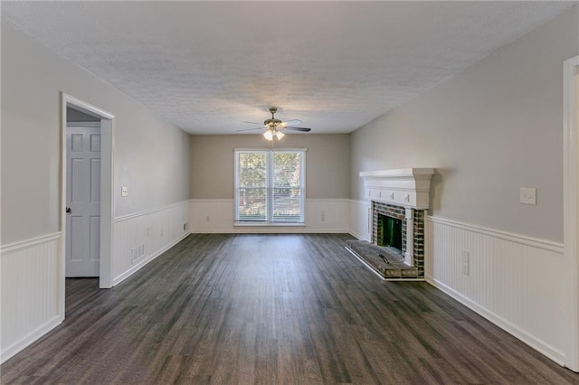 unfurnished living room with a brick fireplace, dark hardwood / wood-style floors, a textured ceiling, and ceiling fan