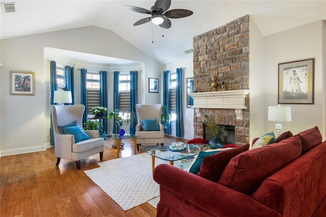 living room featuring hardwood / wood-style floors, ceiling fan, vaulted ceiling, and a brick fireplace