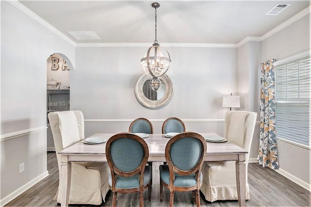 1329 Old Glory Ct, Hoschton, GA 30548 - dining space with a chandelier, wood finished floors, crown molding, and arched walkways