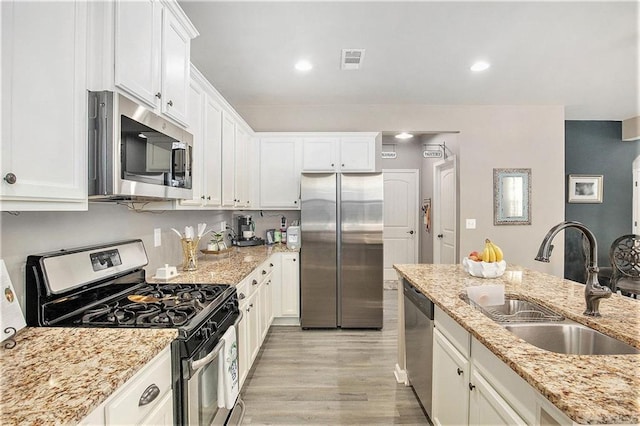 1329 Old Glory Ct, Hoschton, GA 30548 - kitchen with appliances with stainless steel finishes, white cabinetry, light wood finished floors, light stone countertops, and recessed lighting