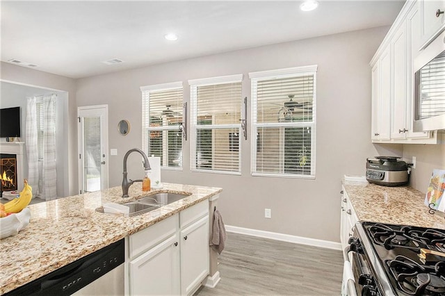 1329 Old Glory Ct, Hoschton, GA 30548 - kitchen with appliances with stainless steel finishes, light wood-style flooring, white cabinetry, light stone countertops, and recessed lighting