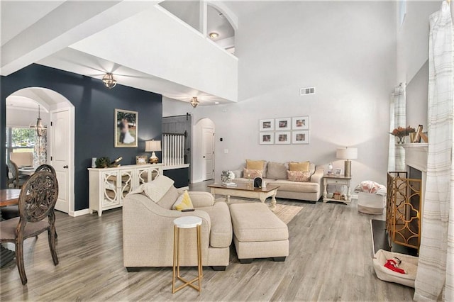 1329 Old Glory Ct, Hoschton, GA 30548 - living area featuring arched walkways, wood finished floors, a fireplace with raised hearth, beamed ceiling, and a towering ceiling