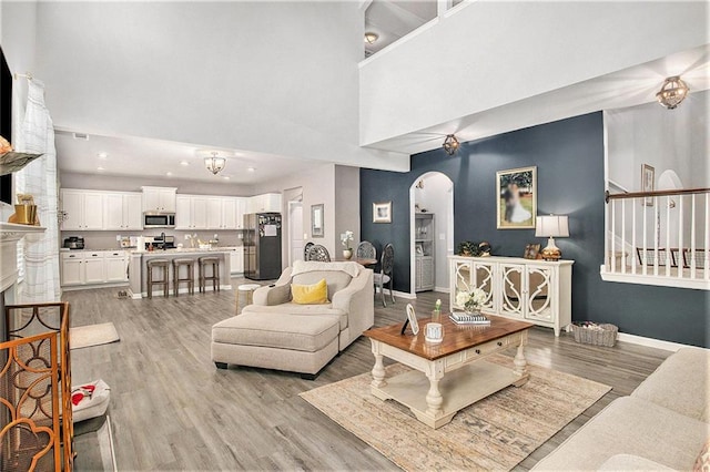1329 Old Glory Ct, Hoschton, GA 30548 - living room featuring arched walkways, a towering ceiling, light wood-style flooring, and recessed lighting