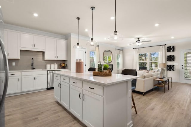 kitchen featuring white cabinets, dishwasher, sink, and hanging light fixtures