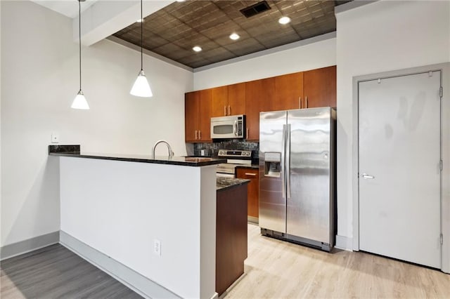 kitchen featuring beamed ceiling, backsplash, decorative light fixtures, appliances with stainless steel finishes, and light wood-type flooring