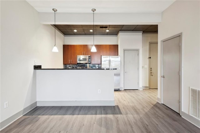 kitchen featuring tasteful backsplash, light hardwood / wood-style flooring, kitchen peninsula, decorative light fixtures, and appliances with stainless steel finishes