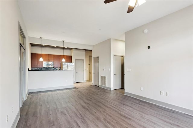 unfurnished living room featuring ceiling fan and light hardwood / wood-style flooring