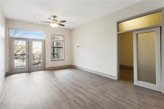 empty room with ceiling fan, french doors, and hardwood / wood-style floors