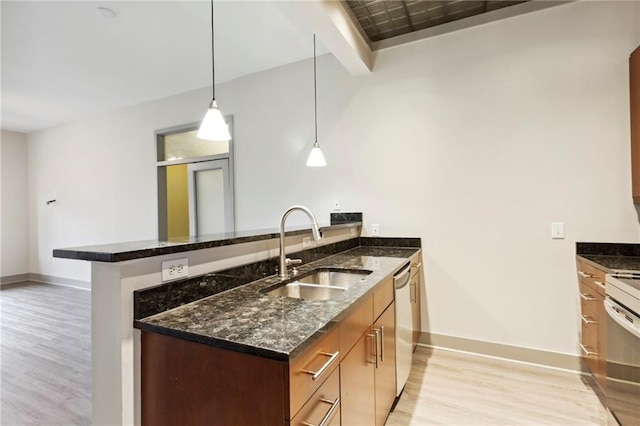 kitchen with pendant lighting, sink, dark stone countertops, light hardwood / wood-style floors, and kitchen peninsula