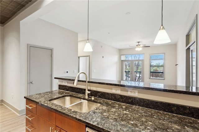 kitchen featuring sink, hanging light fixtures, dark stone counters, and french doors