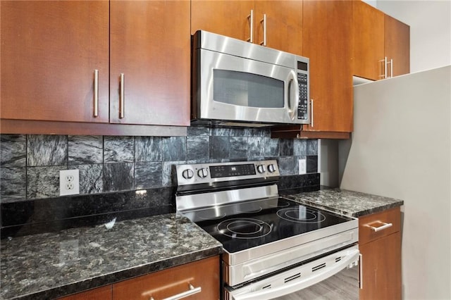 kitchen featuring appliances with stainless steel finishes, backsplash, and dark stone countertops