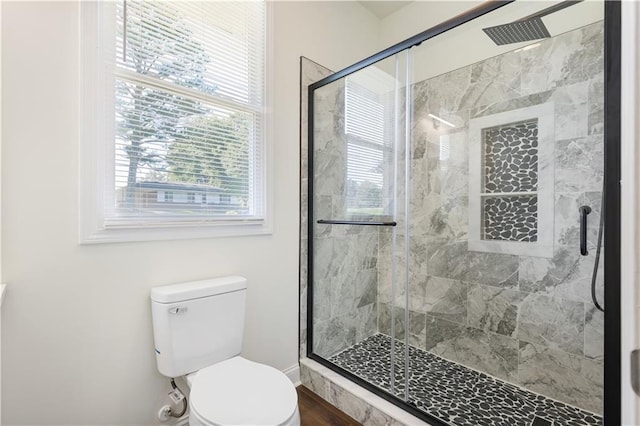 bathroom with a shower with shower door and toilet