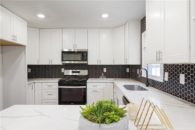 kitchen featuring appliances with stainless steel finishes, sink, white cabinets, and light stone counters