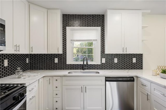 kitchen with sink, white cabinets, backsplash, stainless steel appliances, and light stone countertops