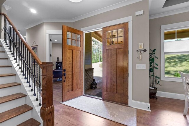 entryway with ornamental molding and hardwood / wood-style floors