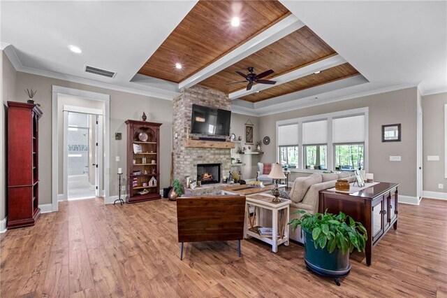 living room featuring a stone fireplace, wood ceiling, hardwood / wood-style flooring, ornamental molding, and ceiling fan