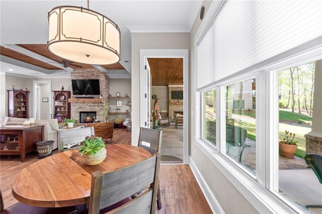 dining area featuring crown molding, wood-type flooring, and a fireplace