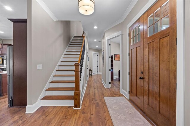 foyer entrance with hardwood / wood-style flooring and ornamental molding