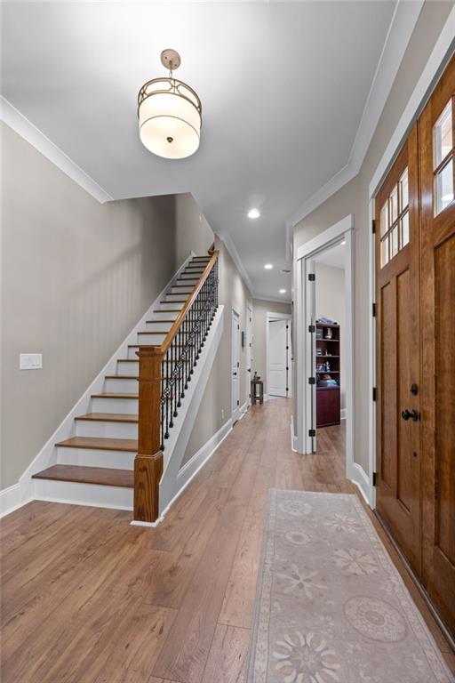 foyer entrance featuring crown molding and hardwood / wood-style flooring