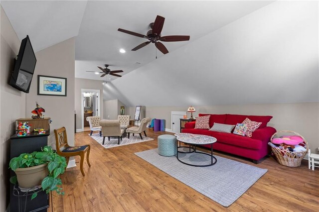 living room with ceiling fan, wood-type flooring, and vaulted ceiling