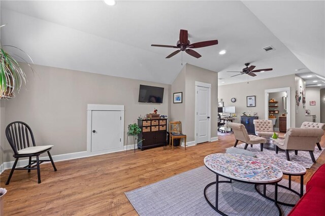 living room featuring ceiling fan, lofted ceiling, and light wood-type flooring