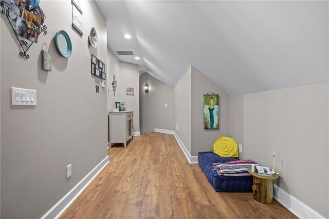 hall featuring light wood-type flooring and vaulted ceiling