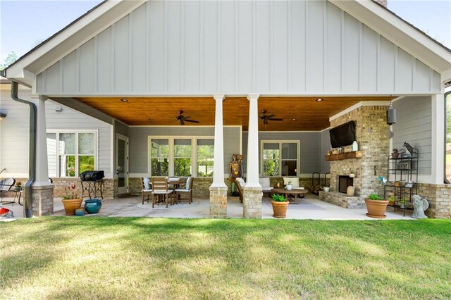 back of house with a patio area, a yard, an outdoor living space with a fireplace, and ceiling fan