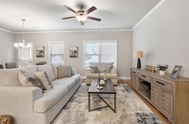 living room with ceiling fan with notable chandelier, ornamental molding, and light wood-type flooring