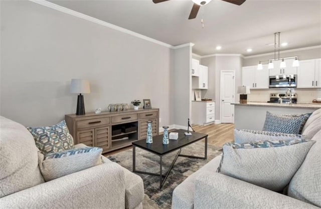 living room with crown molding, ceiling fan, and light wood-type flooring