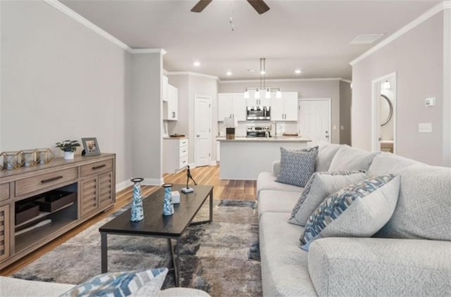 living room with crown molding, ceiling fan, and light wood-type flooring