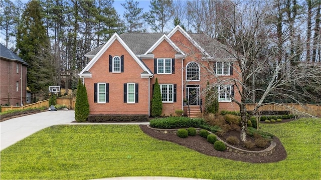 view of front facade with fence, a front lawn, and brick siding