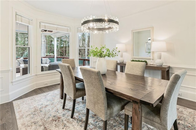 dining area featuring a chandelier, a decorative wall, wood finished floors, wainscoting, and crown molding