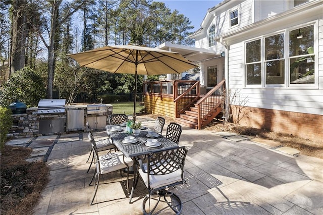 view of patio with an outdoor kitchen, outdoor dining area, area for grilling, and a wooden deck