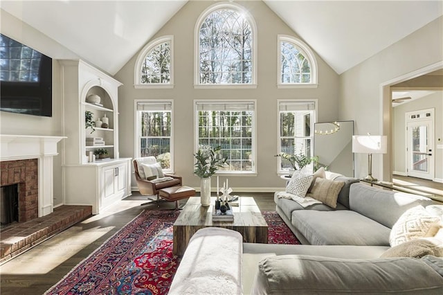 living room featuring baseboards, a fireplace, high vaulted ceiling, and wood finished floors