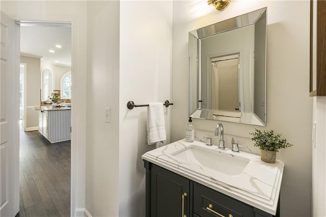 bathroom with recessed lighting, wood finished floors, vanity, and baseboards