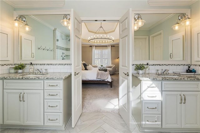 full bath with a chandelier, two vanities, a sink, and crown molding