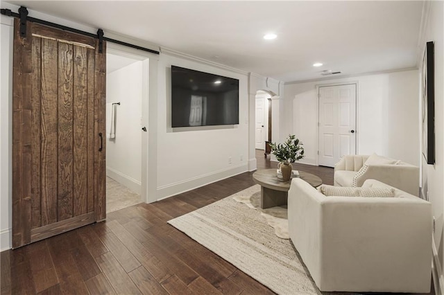 living room with a barn door, baseboards, visible vents, arched walkways, and wood finished floors