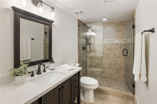 bathroom featuring toilet, a stall shower, vanity, and visible vents