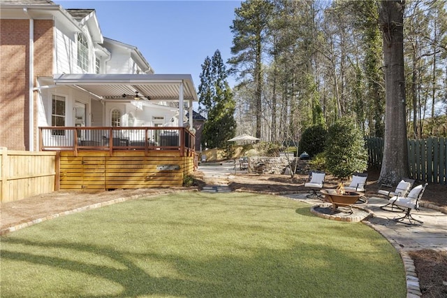 view of yard with a patio, fence, a wooden deck, and a ceiling fan