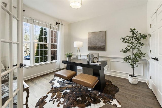 office space with dark wood-type flooring, wainscoting, and a decorative wall