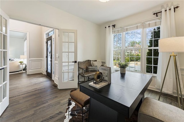 office area with french doors, dark wood finished floors, lofted ceiling, a decorative wall, and wainscoting