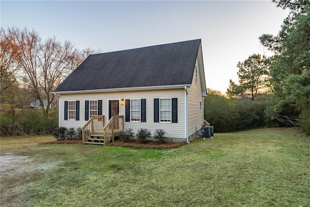 cape cod home with central air condition unit and a yard