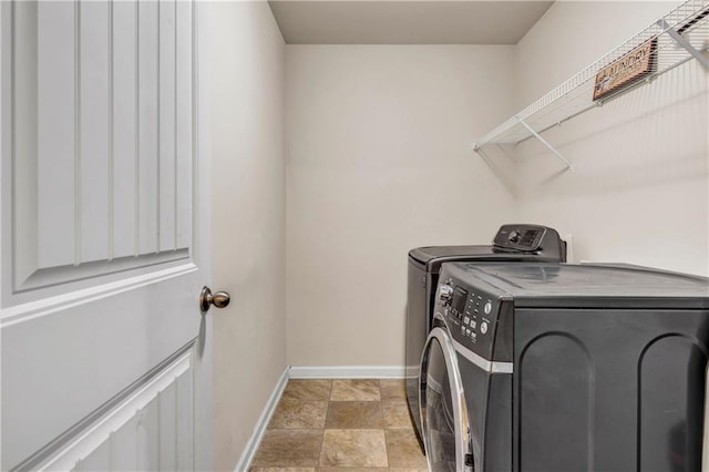 laundry area with laundry area, washer and clothes dryer, and baseboards