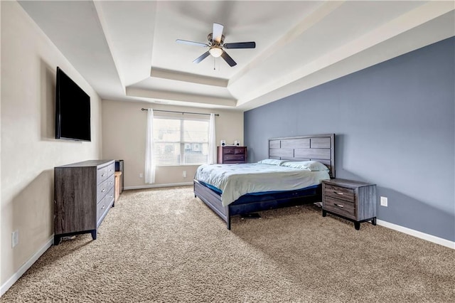 bedroom with a tray ceiling, light carpet, and baseboards