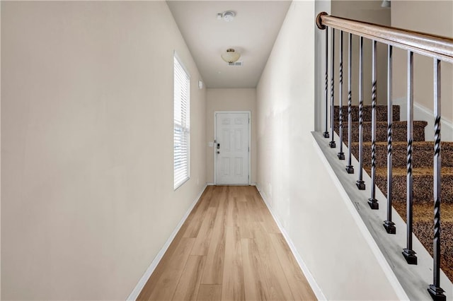 hall with baseboards, visible vents, and light wood-style floors