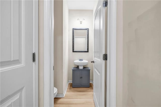 half bathroom featuring a sink, wood finished floors, and toilet