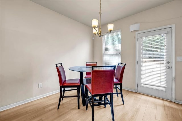 dining area featuring baseboards, light wood-type flooring, and an inviting chandelier