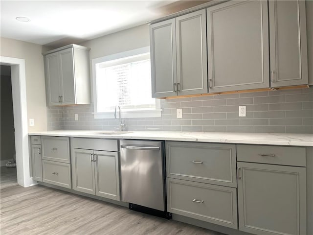 kitchen with gray cabinetry, sink, light stone counters, and light hardwood / wood-style flooring