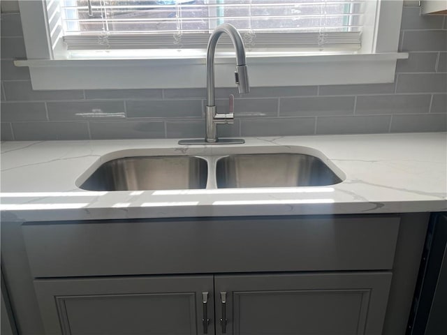 details featuring sink, backsplash, and light stone counters