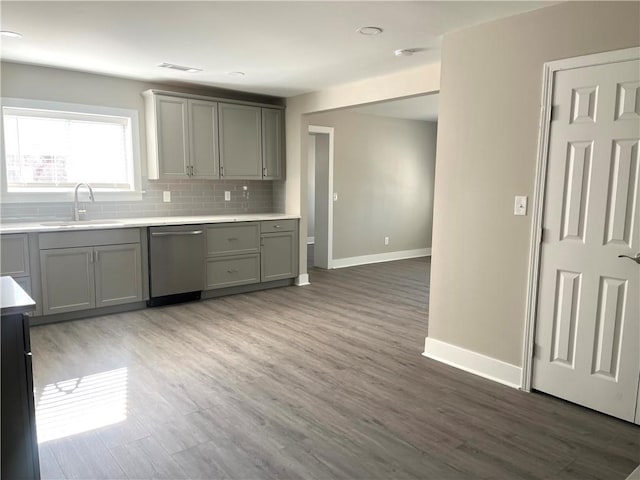 kitchen featuring gray cabinets, dishwasher, sink, and backsplash